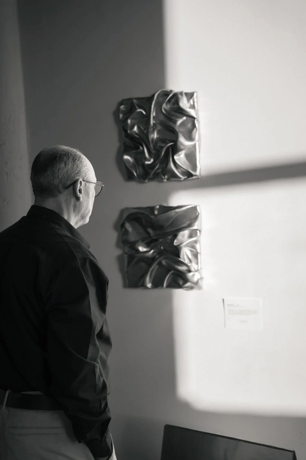 Un visiteur observe le diptyque d’œuvres argentées, noir et blanc