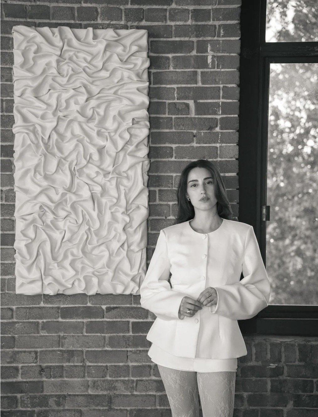 Œuvre murale blanche texturée sur un mur de briques, noir et blanc